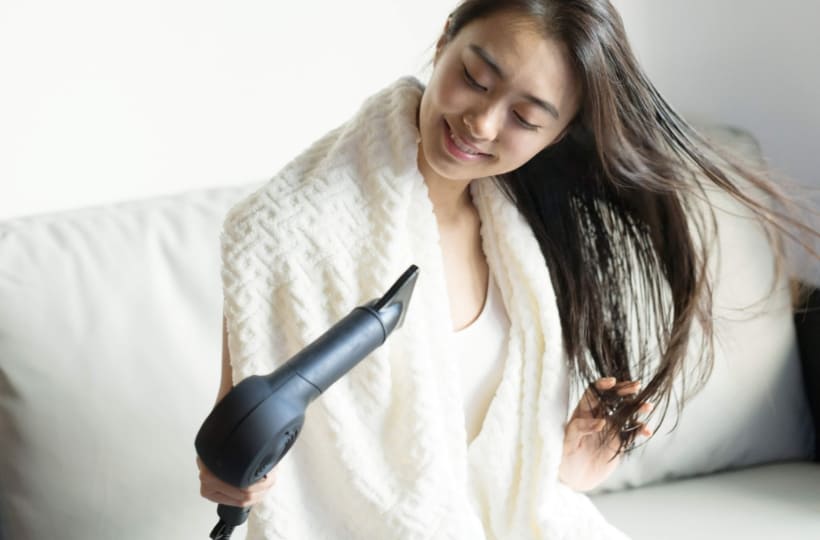 タオルドライ後の髪を根元からドライヤーで乾かす様子
